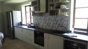 cocina con encimera negra y nevera en Guest House Pilskalni, en Rubene