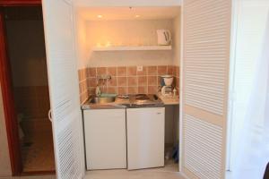 uma pequena cozinha com armários brancos e um lavatório em Ariel apartmanok em Siófok