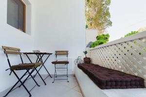 a bench on a balcony with a table and stools at Marilias Apartment in Kamari
