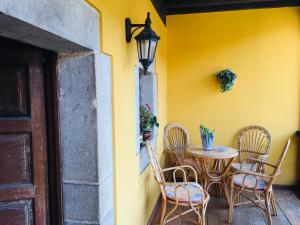 a table and chairs sitting next to a yellow wall at La Corrolada in Avín