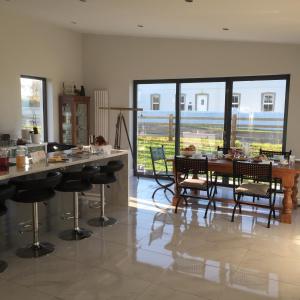 una sala da pranzo con tavoli, sedie e ampie finestre di Farmhouse Boutique a Ballyheige
