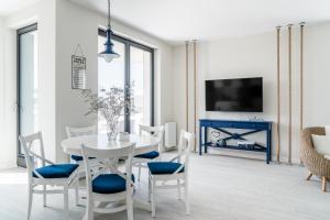 een witte eetkamer met een witte tafel en stoelen bij Lion Apartments - Blue Marina Premium Apartment Okrzei 21 in Sopot