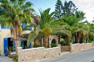 a stone fence with palm trees in front of a building at Hotel Zeus in Kamari