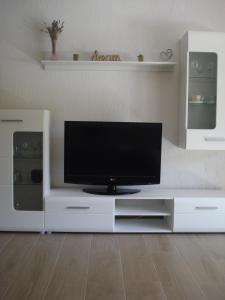 TV de pantalla plana en un centro de entretenimiento blanco en Apartment Premantura, en Premantura