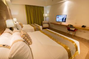 a hotel room with two beds and a television at Ferra Hotel and Garden Suites in Boracay