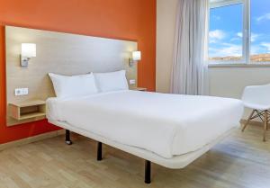 
a white bed sitting in a room next to a window at B&B Hotel Madrid Las Rozas in Las Rozas de Madrid
