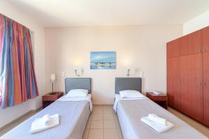 a hotel room with two beds and a window at Olympic Suites in Rethymno