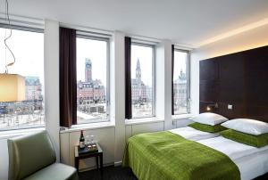 um quarto com uma cama com um cobertor verde e janelas em The Square em Copenhague