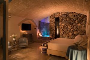 a bedroom with a bed and a stone wall at Hotel Don Ferrante in Monopoli