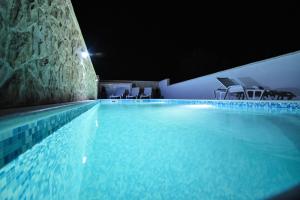 ein großer Pool mit blauem Wasser in der Nacht in der Unterkunft Apartmani Lukic in Vir