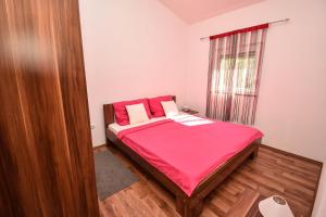 ein Schlafzimmer mit einem Bett mit roten Laken und einem Fenster in der Unterkunft Apartmani Lukic in Vir + 36 Fotos