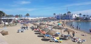 una playa con mucha gente y sombrillas en Apartment Serna, en Marbella