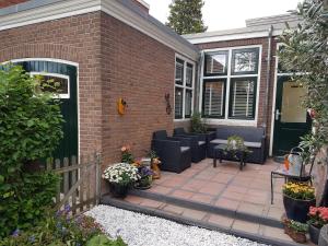 een stenen huis met een patio met banken en bloemen bij Het prinsentuintje in Leeuwarden