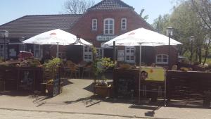 two white umbrellas in front of a building at Haus Schwalbennest H5 in Butjadingen