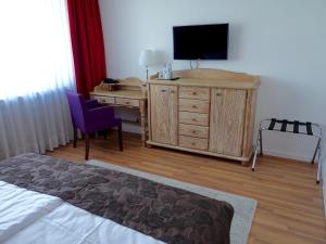 ein Schlafzimmer mit einem Schreibtisch und einem TV auf einer Kommode in der Unterkunft Stadthotel Langenfeld in Langenfeld