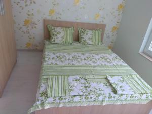 Schlafzimmer mit einem Bett mit einer grünen und weißen Bettdecke in der Unterkunft Private apartment in Faith - Ravda in Rawda