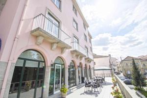 um edifcio cor-de-rosa com uma varanda numa rua em Hotel Eurosol Gouveia em Gouveia