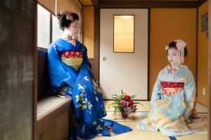 Dos mujeres en kimonos sentadas en una habitación en Stay SAKURA Kyoto Toji Machiya, en Kioto