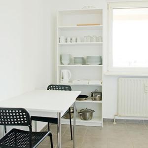 eine Küche mit einem weißen Tisch und Stühlen und einem Regal in der Unterkunft Ferienwohnung Buffon in Wertheim + 3 Fotos