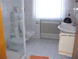 ein weißes Bad mit einem WC und einem Waschbecken in der Unterkunft pension Helga in Bad Dürkheim