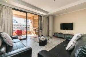 uma sala de estar com um sofá e uma televisão de ecrã plano em 207 Raphael Penthouse em Joanesburgo