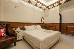 1 dormitorio con 1 cama y 1 silla en 澎湖夏ㄧ棧民宿, en Magong