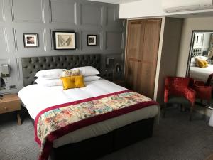 1 dormitorio con 1 cama grande con almohadas amarillas en The Angel Hotel, en Leamington Spa