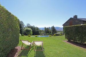 a pair of chairs sitting in a yard next to a hedge at Tpa Casa en Pleta de Saga con piscina para 6/8 personas in Ger