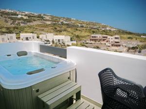 a hot tub on top of a balcony with a chair at Valery Suites in Fira