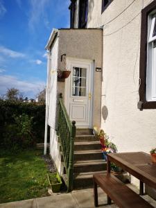 a white door on a white house with stairs at Rose cottage in Millport