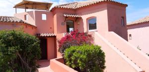 une maison avec des murs roses et des fleurs dans les escaliers dans l'établissement mare natura confort... il mio paradiso in Sardegna, à Isola Rossa