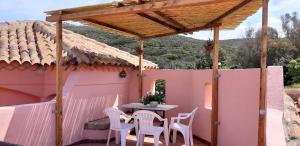 d'une terrasse avec une table et des chaises sous une pergola. dans l'établissement mare natura confort... il mio paradiso in Sardegna, à Isola Rossa