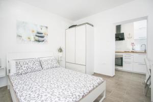 a white bedroom with a bed and a kitchen at Modern Living in the Heart of Trogir in Trogir
