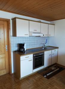 a kitchen with white cabinets and a sink and a stove at Ferienhof Jungkunz in Schwarzenbach am Wald