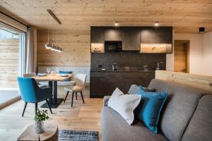 sala de estar y cocina con sofá y mesa en Les Dolomites Mountain Lodges en San Martino in Badia