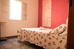 Casa confortável em Guaratinguetá في غواراتينغيتا: غرفة نوم بسرير مع طاولة ولوحة