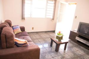 sala de estar con sofá marrón y TV en Casa confortável em Guaratinguetá, en Guaratinguetá