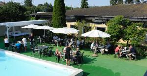 eine Gruppe von Personen, die an Tischen und Sonnenschirmen in der Nähe eines Pools sitzen in der Unterkunft Hotel Balka Strand in Neksø