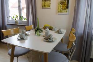 una mesa con sillas y una mesa blanca con tazas y platillos en Ferienwohnung Auf dem Hofe, en Bad Langensalza