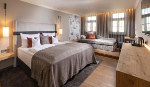ランツフートにあるホテル ゴールデン ゾンネの大きなベッドとソファが備わるホテルルームです。
