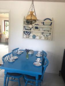 a blue table with chairs and plates and a chandelier at Bed & coffee Hjørring in Hjørring