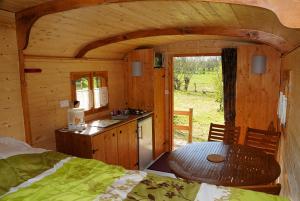 a room with a kitchen and a table in a cabin at La Ferme du Marais Poitevin - Roulotte in Benet