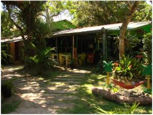 a house with a porch with plants in the yard at Pousada Recanto Tropical in Ilha do Mel