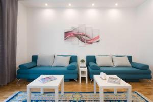 a living room with two blue couches and a painting at City Center Apartments in Zagreb
