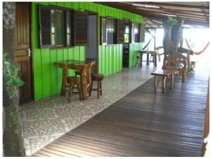 a restaurant with green walls and tables and chairs at Pousada Recanto Tropical in Ilha do Mel