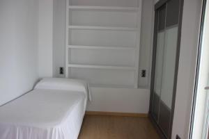Dormitorio blanco con cama y armario en APARTAMENTO BRUSELAS, en Salou