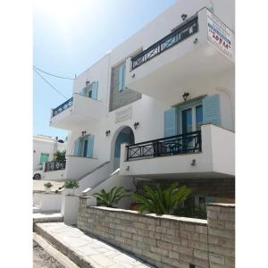 un edificio blanco con ventanas azules y escaleras en Soula Rooms Tinos, en Tinos