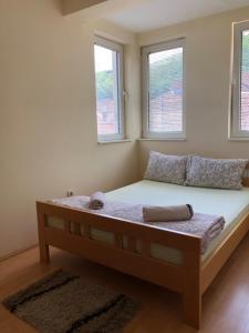 een bed in een kamer met 2 ramen bij Apartmani Jovanovic in Ivanjica