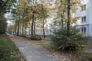 グダニスクにあるPrzestronne czteropokojowe mieszkanie w skandynawskim styluの白い建物前の並木道