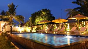 uma piscina com cadeiras e guarda-sóis à noite em Kayuna Villa em Nusa Penida